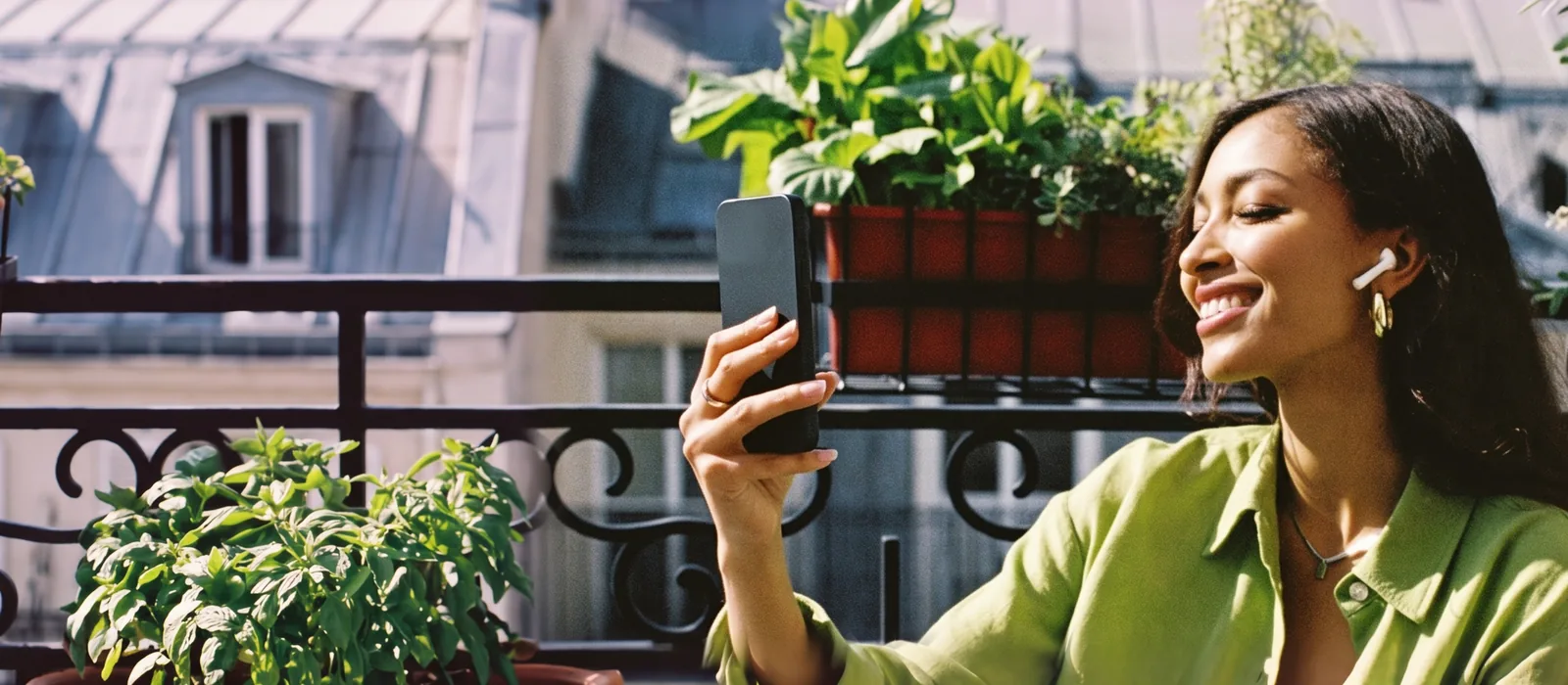 Güneşli bir Paris balkonunda, fıstık yeşili gömlekli bir kadın tek kulağında kulaklıkla telefonuna konuşuyor.